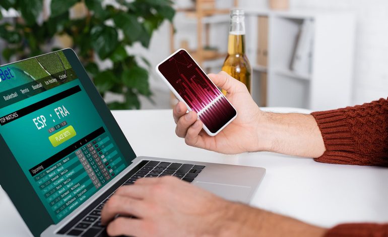 Man gambling online anonymously with a beer bottle beside