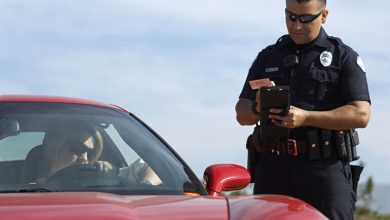 Police officer issuing a traffic ticket to a woman in a red car