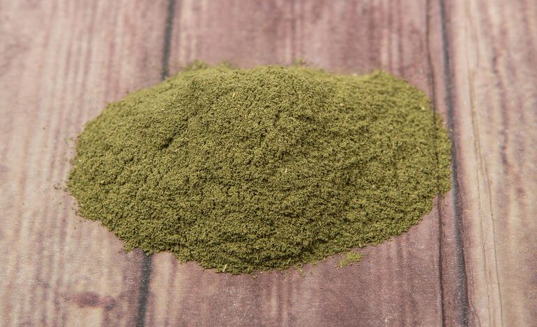 Vein kratom powder neatly spread on a wooden surface to advertise on news websites