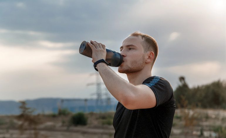 A marathon runner drinking water from a hydration pack while running