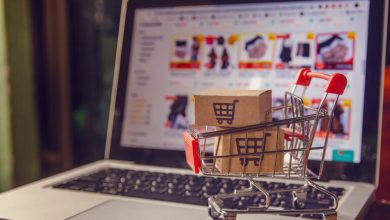 A miniature shopping cart with boxes placed on a laptop displaying a private-level e-commerce site