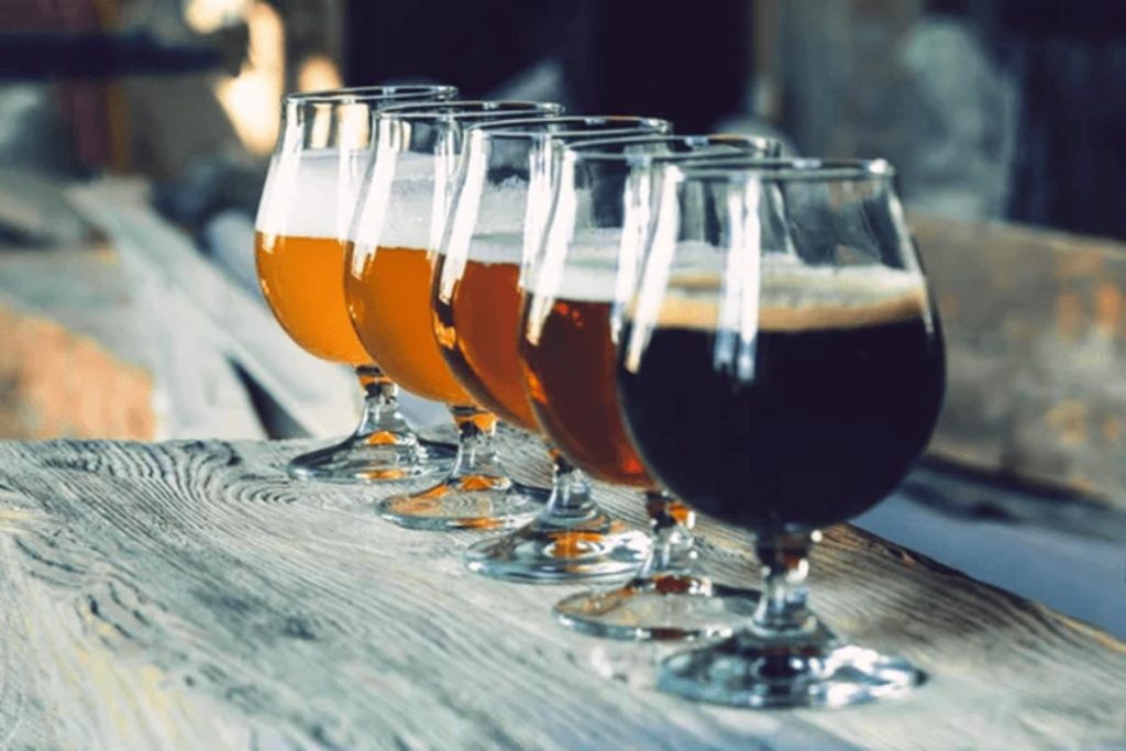 A lineup of craft beer glasses showcasing a variety of beer styles on a rustic wooden surface