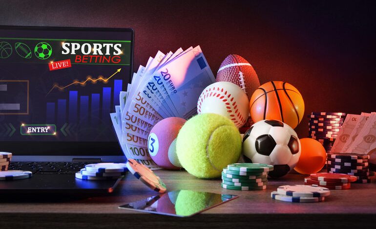 Laptop with sports betting toto sites, sports gear, money, and casino chips on a desk