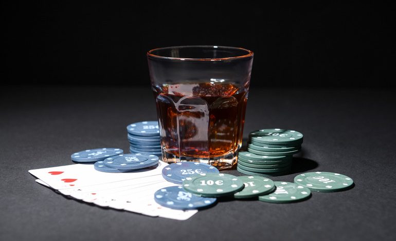 Glass of alcohol with poker chips and playing cards, exploring the psychology of gambling and alcohol