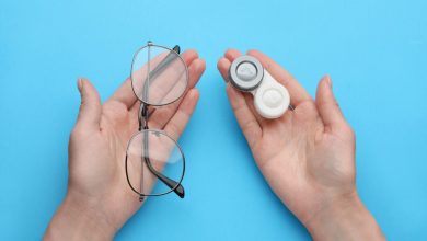 A woman is holding a contact lens and glasses case on a light blue background
