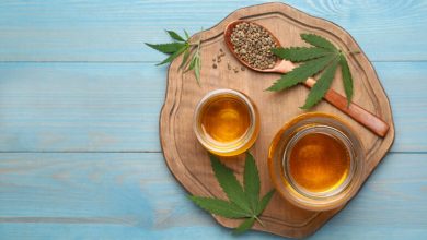 Hemp-infused seltzers and cannabis leaves arranged on a light blue wooden table