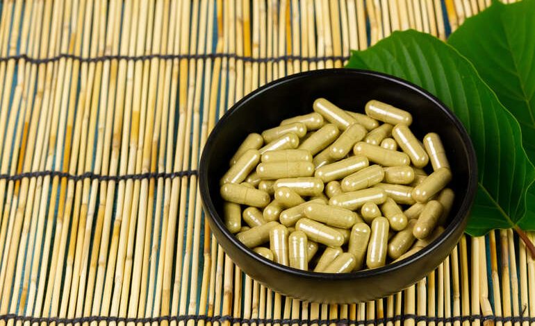 7-OH capsules with a background of kratom leaves