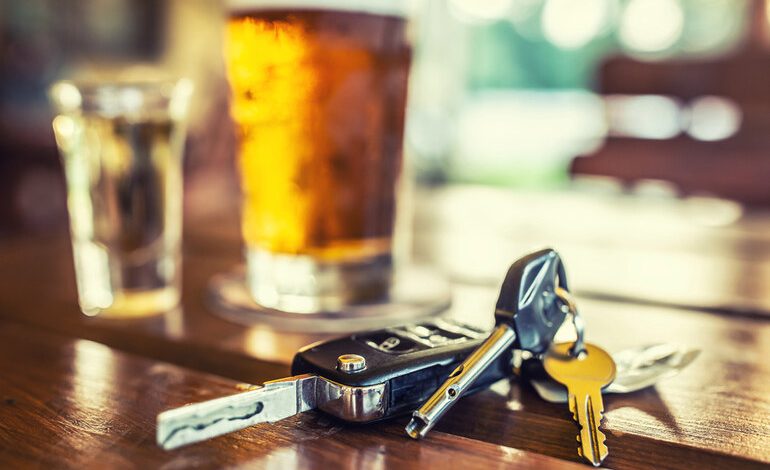 Car keys on a bar table with beer and a shot glass