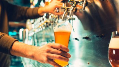 A bartender pouring a hazy craft beer from a tap at a San Diego brewery