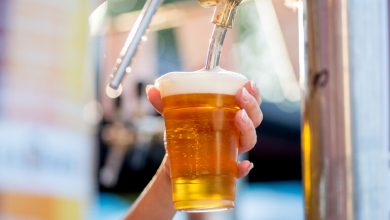 A traveller pouring a glass of golden craft beer from a tap at an outdoor San Diego brewery