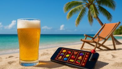 A glass of beer and a smartphone with an online pokies game on a tropical beach