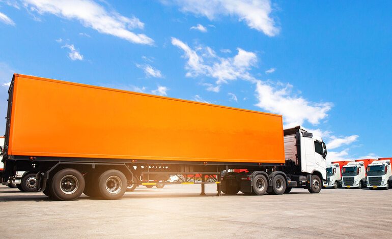 Orange semi-truck parked at a Dallas terminal