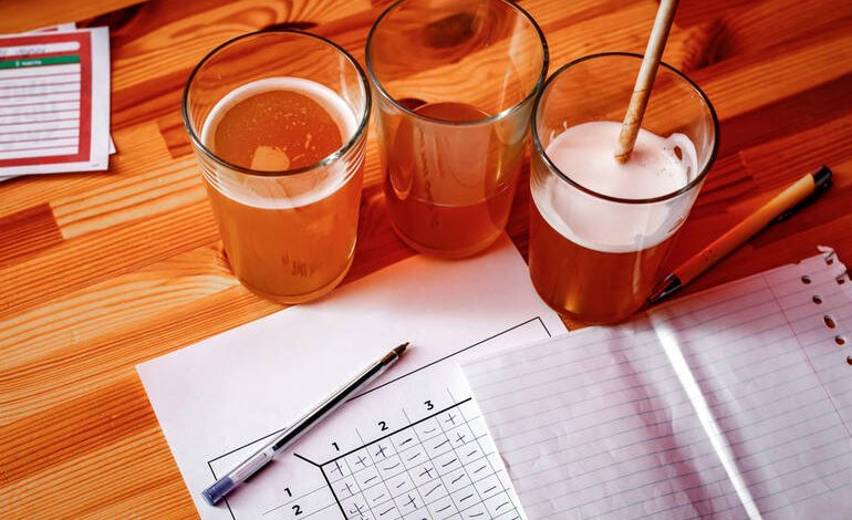 Three glasses of craft beer on a student’s desk with notebooks, pens, and study papers