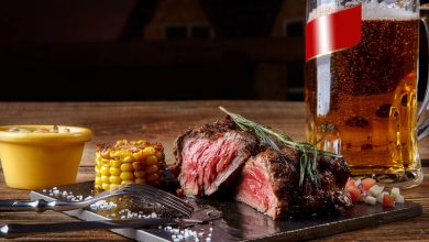 Juicy medium-rare steak served with grilled corn and a frosty mug of craft beer
