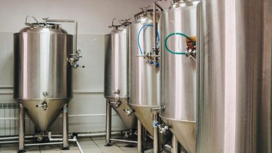 Row of bar stools facing fermentation tanks inside a modern San Diego brewery