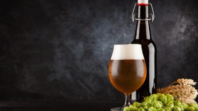 A glass and bottle of craft beer surrounded by fresh hops and barley on a dark background, symbolizing the use of local San Diego ingredients in brewing