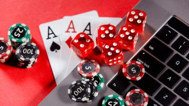 Poker chips, red dice, and playing cards on a laptop keyboard
