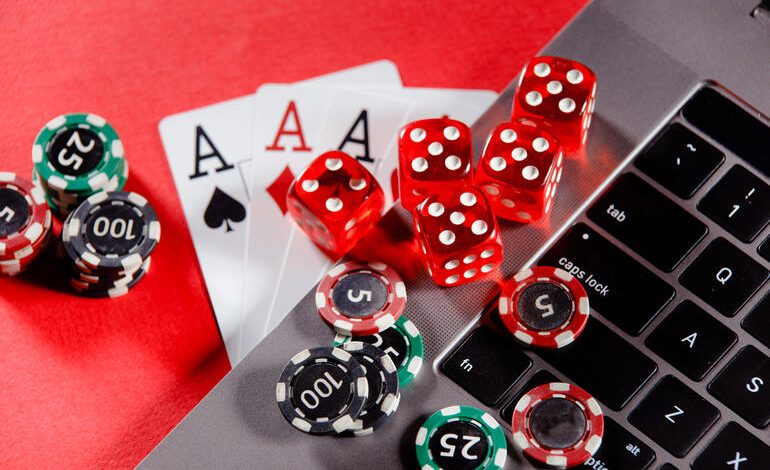 Poker chips, red dice, and playing cards on a laptop keyboard