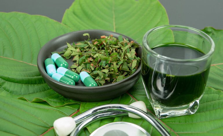 Traditional tea setup with kratom or kava leaf, herbal tea set, and dried herbal root on a wooden tray.