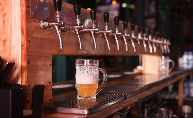 A row of beer taps at a San Diego brewery with a freshly poured glass of craft beer, highlighting local brewing culture and house yeast strains