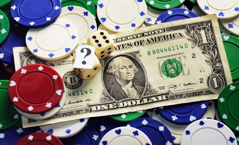 A one-dollar bill surrounded by poker chips and dice, symbolizing low-stakes online gambling