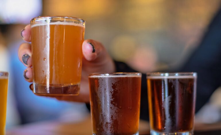 Close-up of a beer with a hand holding a tasting glass at a San Diego brewery