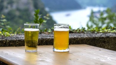 Two glasses of beer on a wooden table overlooking a scenic mountain and river outside the USA