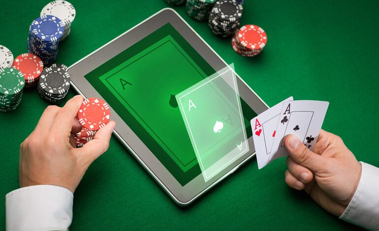 A person playing online poker on a tablet with poker chips and aces in hand