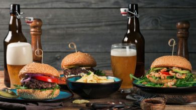Gourmet burgers, chips, and craft beers on a wooden table for a cannabis beer and food pairing guide