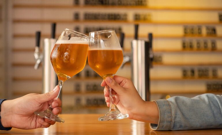 Two people clinking glasses of craft beer at a San Diego brewery