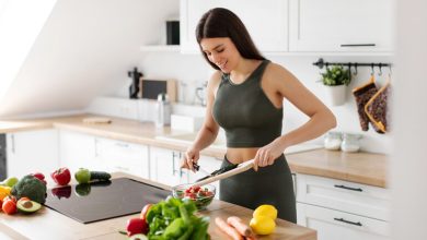 Woman in athletic wear making a vegetable salad as part of her wellness routine