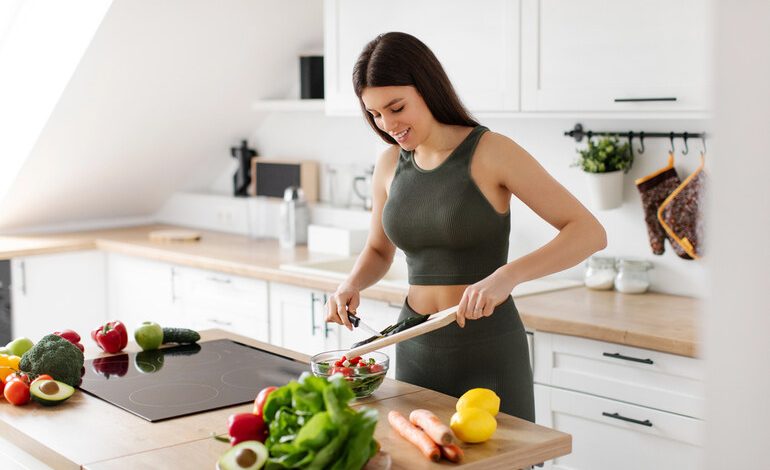 Woman in athletic wear making a vegetable salad as part of her wellness routine