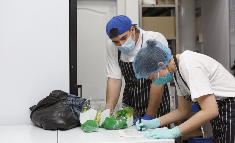 Staff in the brewery kitchen wearing masks and gloves, checking health and safety standards during the cleaning process.