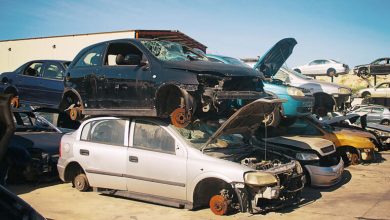 Junkyard cars stacked for parts comparison to online auto auctions.