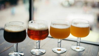 Different types of beer served in clear glasses on a wooden surface.