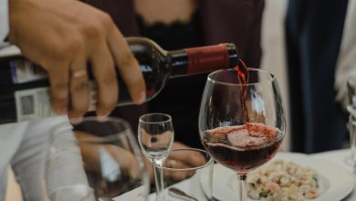 A person pouring red wine into a glass at a dinner party