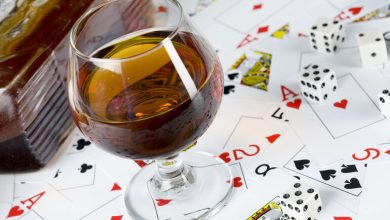 Glass of alcohol with playing cards and dice symbolizing the influence of drinking on casino gaming decisions.
