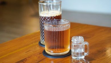 Three glasses with different beverages on a wooden table, showcasing a calm beer-tasting setup for balanced flavor and budget enjoyment.