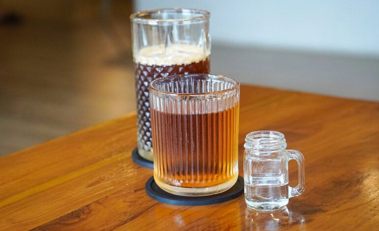 Three glasses with different beverages on a wooden table, showcasing a calm beer-tasting setup for balanced flavor and budget enjoyment.