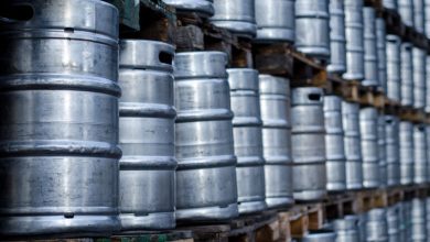 Rows of metal beer kegs stacked on wooden pallets in a storage area.