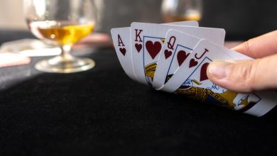A close-up of a person holding a royal flush in hearts during a card game