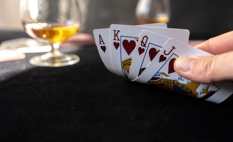 A close-up of a person holding a royal flush in hearts during a card game
