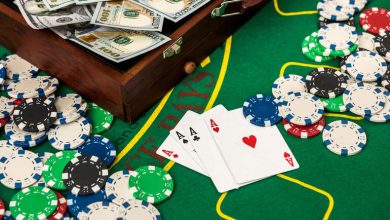 Poker table with playing cards showing four aces, surrounded by casino chips and stacks of hundred-dollar bills.