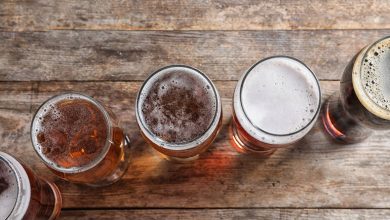A top-down view of five different craft beers in glasses on a rustic wooden table