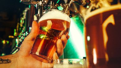 A beer lover is pouring craft beer from a tap into a glass at a brewery with warm lighting