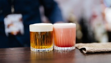 Two glasses of craft beer, one amber and one pink, sitting on a wooden bar counter in a San Diego brewery, representing craft beer culture and financial balance.