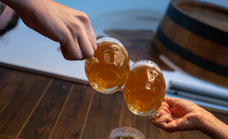 Friends clinking beer mugs together at a rustic bar, symbolizing the relaxed beachside brewery culture in San Diego.