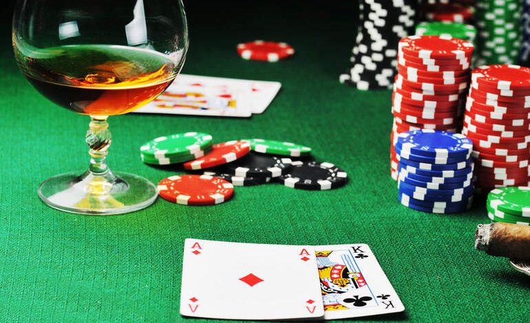 Glass of whiskey, poker cards, and colorful chips on a casino table symbolizing smarter gambling choices by drinking less alcohol.