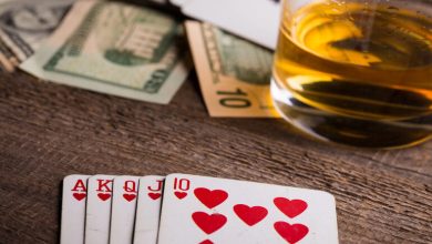 Royal flush in hearts with cash and beer on a wooden table, poker winning hand concept.