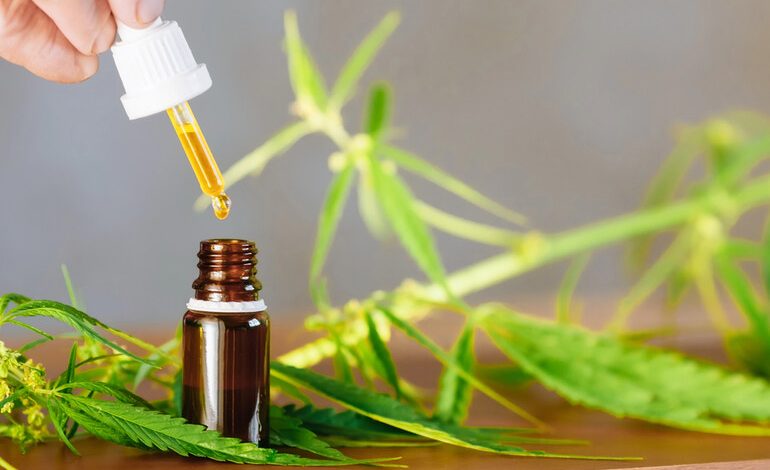 A dropper dispensing golden cannabis oil into a small amber bottle